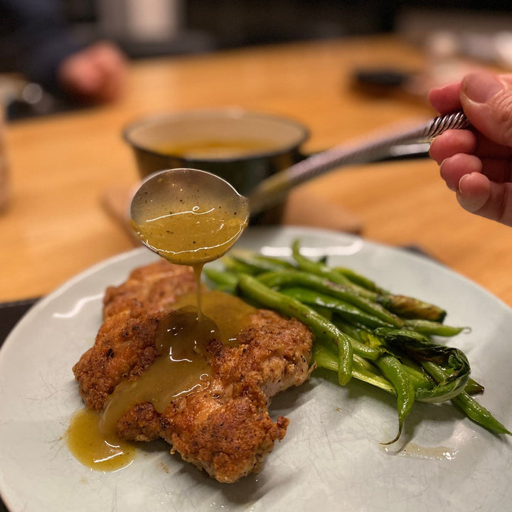 Image of garlic pepper sauce being spooned onto garlic pepper chicken schnitty